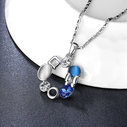 A unique design of combined ornaments plated with platinum, inlaid with white opal, blue glass stone and a crystal diamond